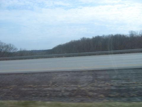 1978 Ford Bronco - View from a vehicle traveling on a highway, showing a guardrail and wooded hills.