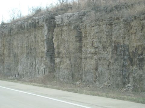 1978 Ford Bronco - A road passes by a large rock cliff face with sparse vegetation.