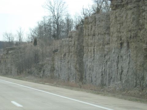 1978 Ford Bronco - A view of a large rock formation next to a highway, with trees visible on the upper ledge.