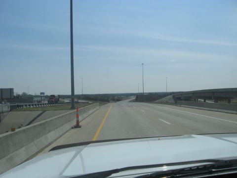 1978 Ford Bronco - A view from a vehicle driving on a highway, with other vehicles visible in the distance and a clear blue sky overhead.