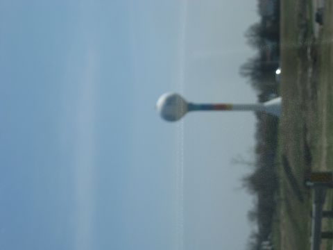 1978 Ford Bronco - A water tower stands tall against a clear blue sky, with a hint of rainbow colors on its support.