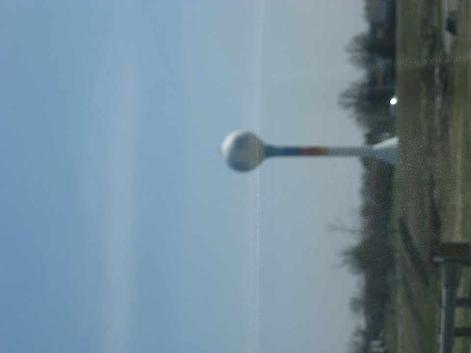 Water tower with rainbow stripe against blue sky