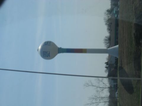 1978 Ford Bronco - A water tower stands tall against a clear blue sky, with colorful bands adorning its support structure.