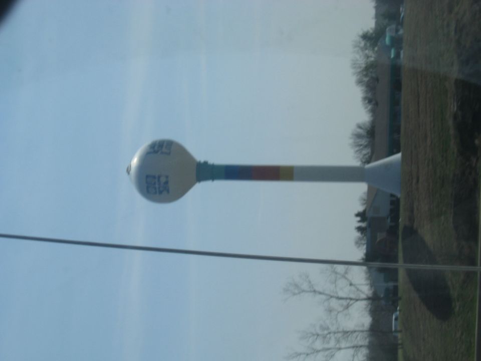 Water tower with blue text reading "CKS" and colored bands on its support