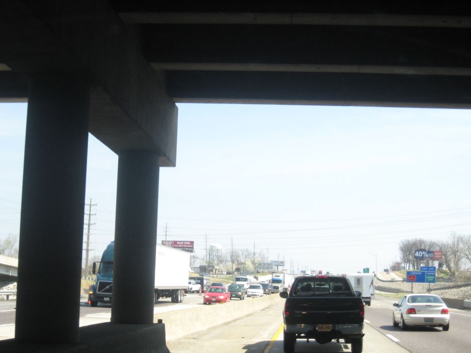 Black pickup truck on highway under concrete overpass, other vehicles visible