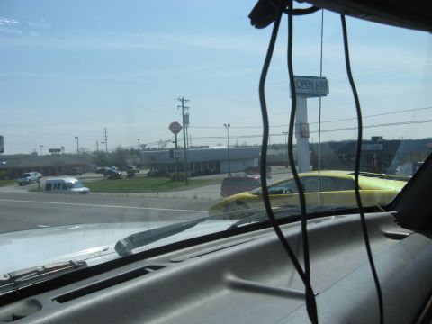 1978 Ford Bronco - A yellow sports car is visible on the road next to other vehicles and commercial buildings.