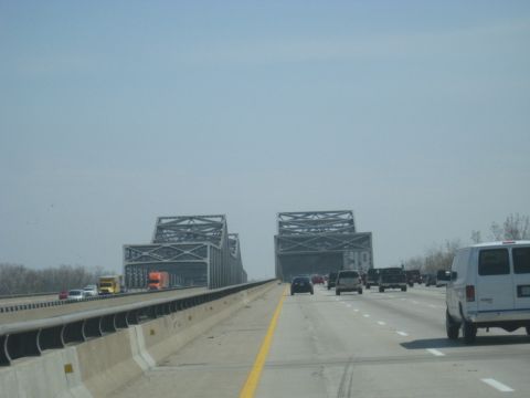 1978 Ford Bronco - A white van travels on a highway, passing under a large, industrial bridge structure.