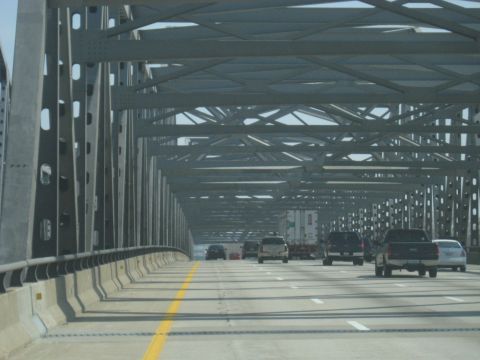 1978 Ford Bronco - Vehicles travel across a large metal bridge under a clear sky.