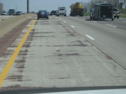 1978 Ford Bronco - A blue car with white racing stripes travels down a highway, passing other vehicles.