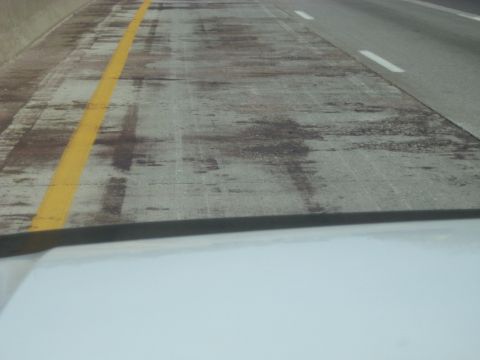 1978 Ford Bronco - A view of highway lane markings on a concrete road surface, with a yellow line and white dashes visible.
