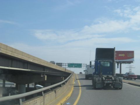 1978 Ford Bronco - A blue semi-truck is seen from behind on a highway, with a red car and a billboard in the background.