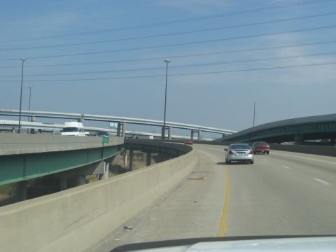 1978 Ford Bronco - Multiple vehicles travel on a highway with complex overpasses under a clear sky.