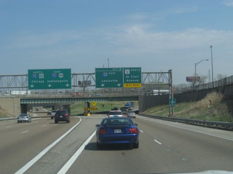 1978 Ford Bronco - A blue Ford Mustang is seen on the highway, with multiple traffic signs overhead.