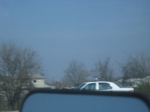 1978 Ford Bronco - A white sedan, possibly a police car, is visible in the distance under a hazy sky.