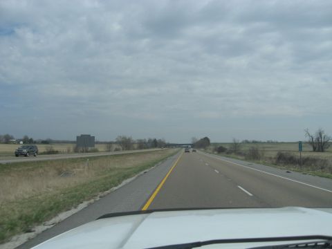1978 Ford Bronco - Driving on a highway with a cloudy sky and open fields beside the road.