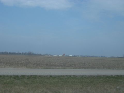 1978 Ford Bronco - A distant farmstead is visible across a vast, harvested agricultural field.
