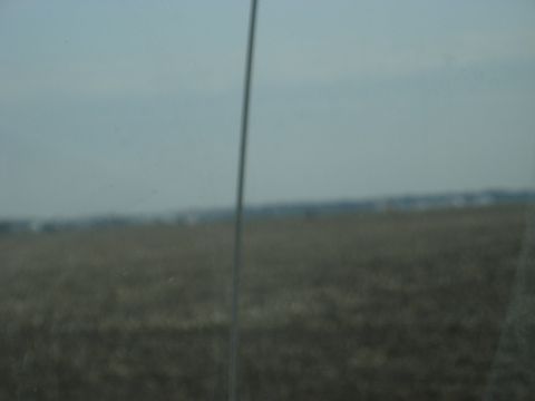 1978 Ford Bronco - A blurry scene of a field under a hazy sky, with a thin vertical line obscuring the view.