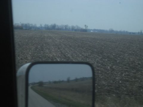1978 Ford Bronco - A reflection in a side mirror shows a road and a barren field, hinting at a journey through the countryside.