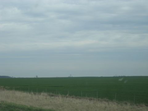 1978 Ford Bronco - A wide expanse of green farmland is visible under a hazy, overcast sky.