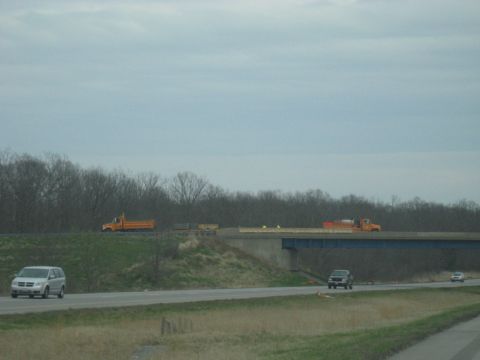 1978 Ford Bronco - Multiple construction trucks are visible on a highway overpass during the day.