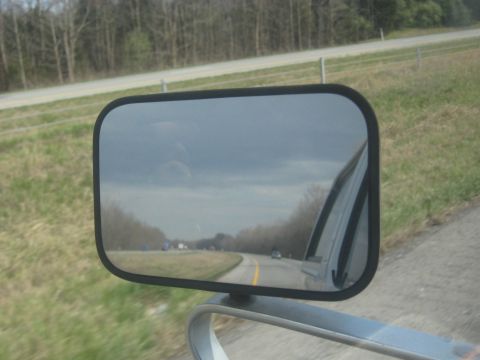 1978 Ford Bronco - View from a side mirror shows a highway with traffic and trees lining the road.