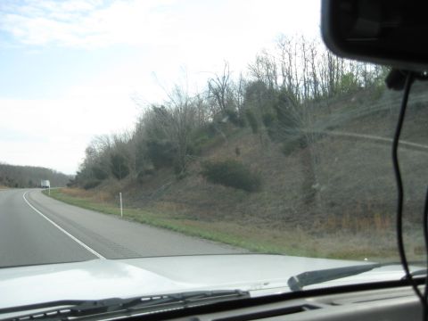 1978 Ford Bronco - A truck travels down a highway on a cloudy day, viewed from the perspective of another vehicle.