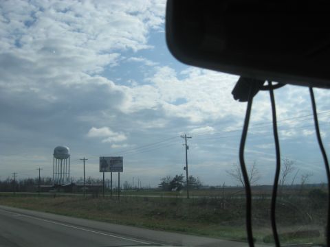1978 Ford Bronco - A water tower and a billboard are visible from the road on a cloudy day.