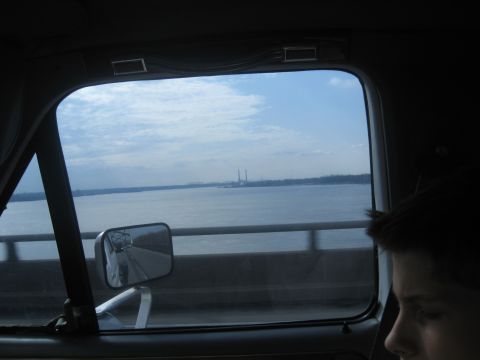1978 Ford Bronco - Looking out the window of a vehicle at a wide river with industrial smokestacks in the distance.