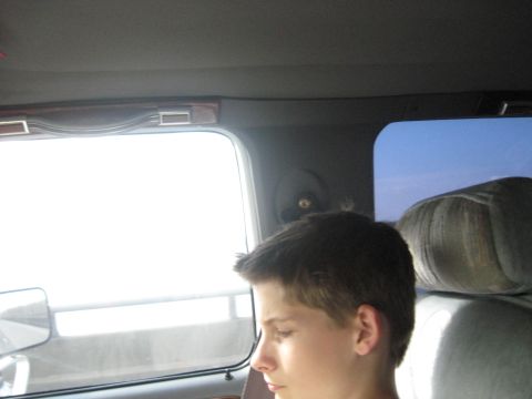 1978 Ford Bronco - A young boy sits inside a vehicle, gazing out the window at the bright sky.