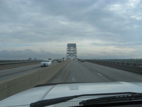 1978 Ford Bronco - Traffic moves along a highway with a distinctive bridge tower visible ahead under a cloudy sky.