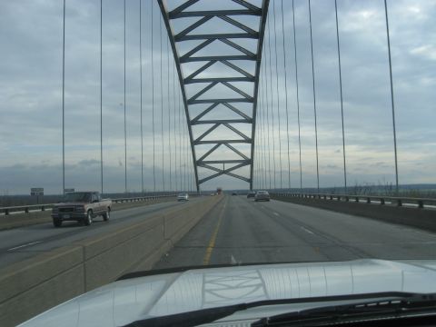 1978 Ford Bronco - A pickup truck travels across a large suspension bridge, with the bridge's structure dominating the view.