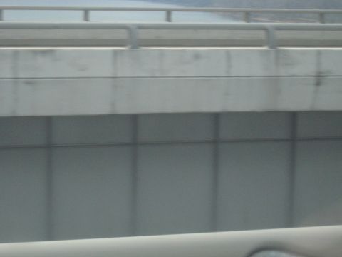1978 Ford Bronco - The view from a car shows a concrete overpass with a railing and a body of water in the distance.