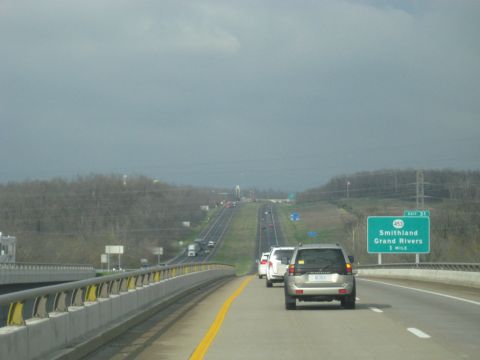 1978 Ford Bronco - Traffic moves along a highway under a cloudy sky, with an exit sign visible.