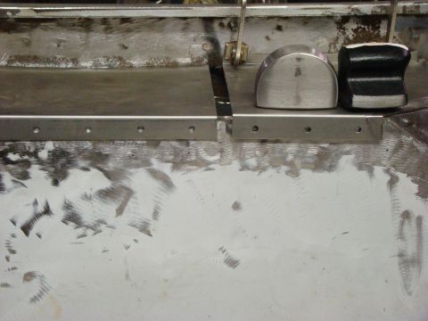 1948 Jeep Wrangler - Close-up of a metal panel showing recent grinding and repair work, with two metal blocks resting on its surface.