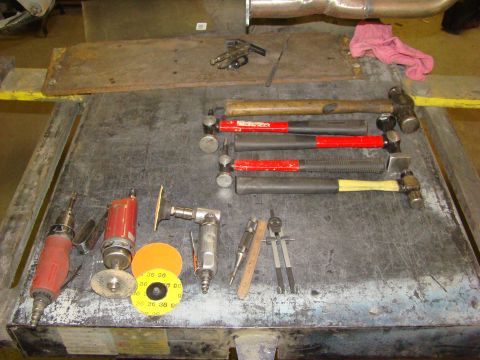 1948 Jeep Wrangler - Various bodywork hammers, dollies, and air tools are laid out on a metal workbench surface.