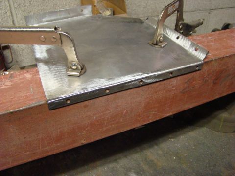 1948 Jeep Wrangler - Metal part being prepared for welding, clamped to a wooden support beam.
