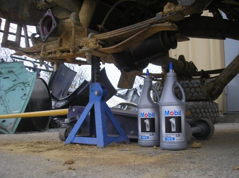 1987 Suzuki Samurai - The rear axle of a vehicle is supported by jack stands, with two bottles of Mobil 1 synthetic gear lubricant nearby.