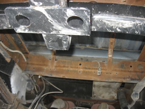 1979 Ford Bronco - The undercarriage of a vehicle displays significant rust on its frame and suspension components.