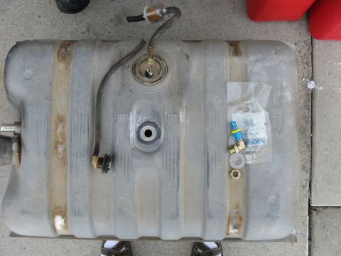 1979 Ford Bronco - Fuel tank assembly with hoses and fittings laid out on concrete.