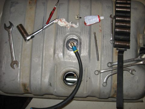1979 Ford Bronco - Tools and a fuel tank are laid out on a surface, suggesting a repair or maintenance task is underway.