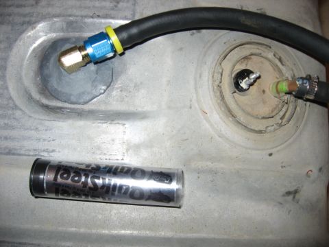 1979 Ford Bronco - A close-up view shows a fuel line connection on a tank, with a tube of QuickSteel repair putty nearby.