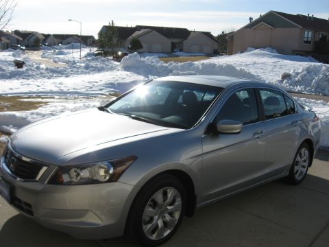2009 Honda Accord - A silver sedan is parked on a concrete driveway with snow piled up around it.