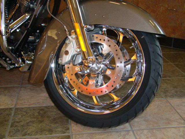 Motorcycle front wheel with chrome spokes and dual brake discs, a gold fender, and chrome engine parts visible