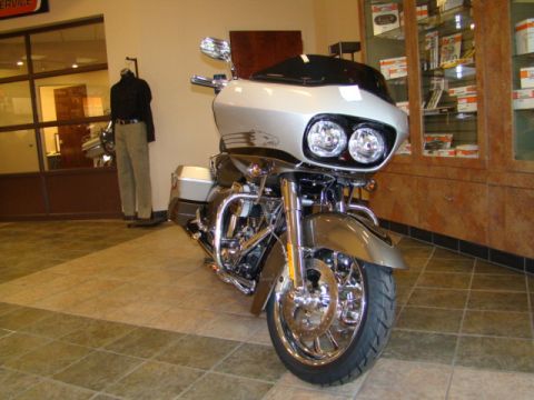 2009 Harley-Davidson FLH - A silver motorcycle with a prominent fairing and dual headlights is displayed inside a showroom.