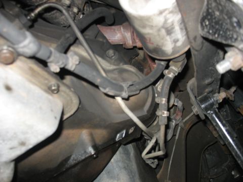1995 Ford C-350 (Centurion Conversions) - Close-up view of engine and transmission components, including hoses and an oil filter.