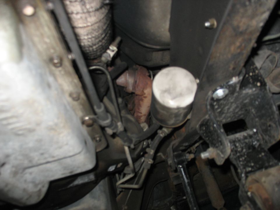 Underside view of vehicle transmission, oil filter, and exhaust components
