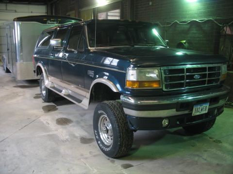 1995 Ford C-350 (Centurion Conversions) - A dark blue Ford SUV is parked indoors, hitched to a silver trailer. The vehicle appears to be a conversion model.