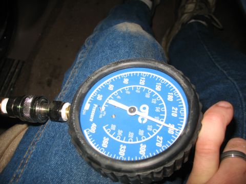 1995 Ford C-350 (Centurion Conversions) - A blue compression gauge is held against a person's leg, showing pressure readings.