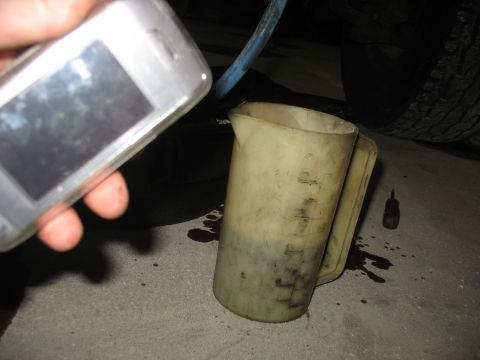 1995 Ford C-350 (Centurion Conversions) - Checking fluid levels with a measuring cup and a cell phone.