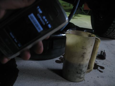 1995 Ford C-350 (Centurion Conversions) - A phone is held over a measuring jug during what appears to be an oil change.